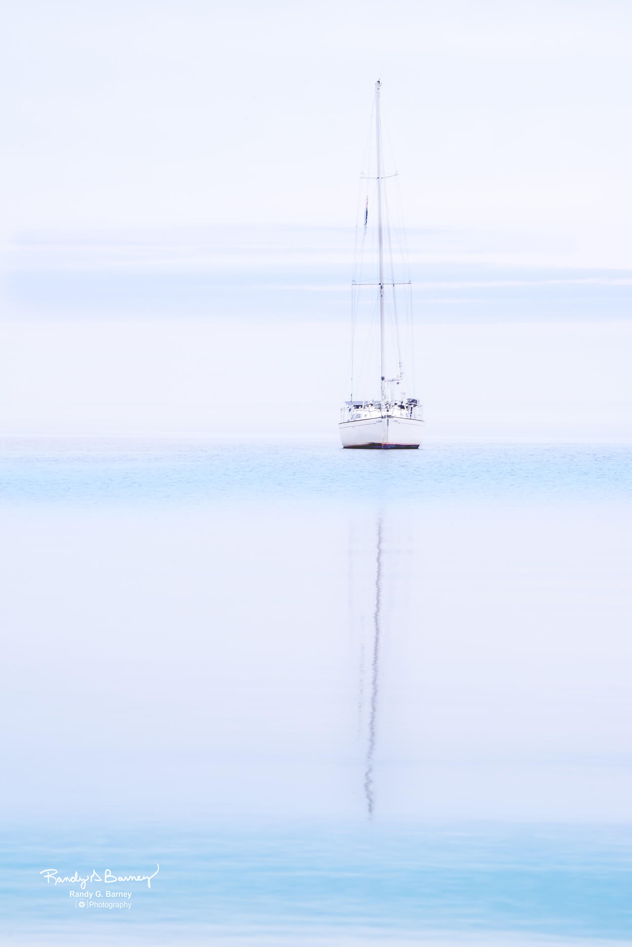 Single Sail Boat in the mist with reflection on water - Copyright Randy G. Barney