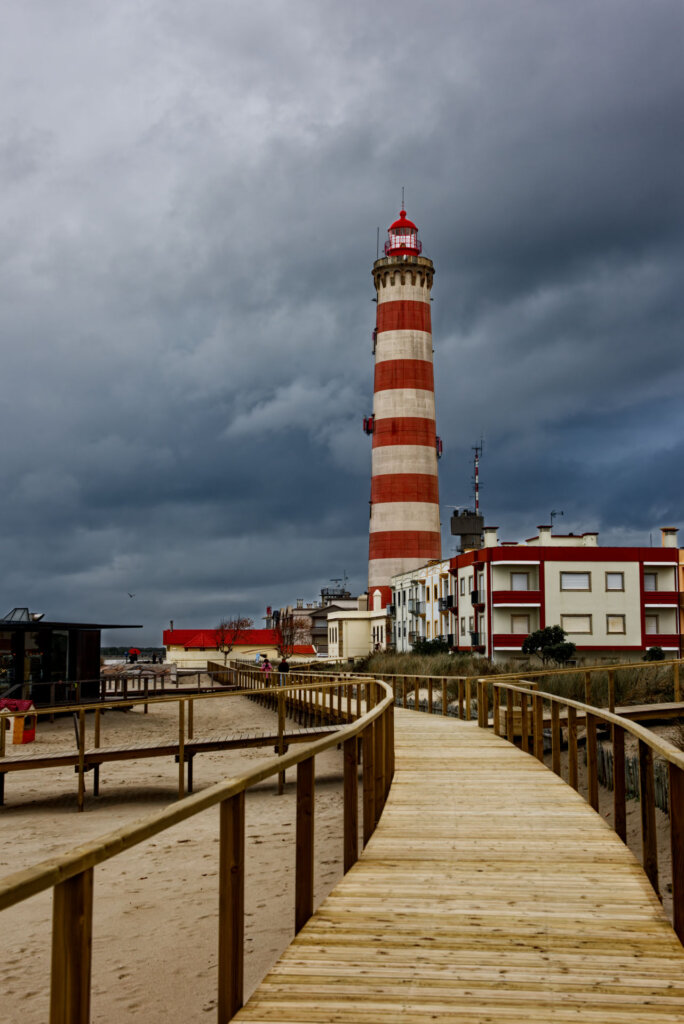 The Barra Lighthouse stands at the edge of the city near Aviero Portugal. In the background is imminent weather coming from far out to sea - Copyright Randy G Barney.